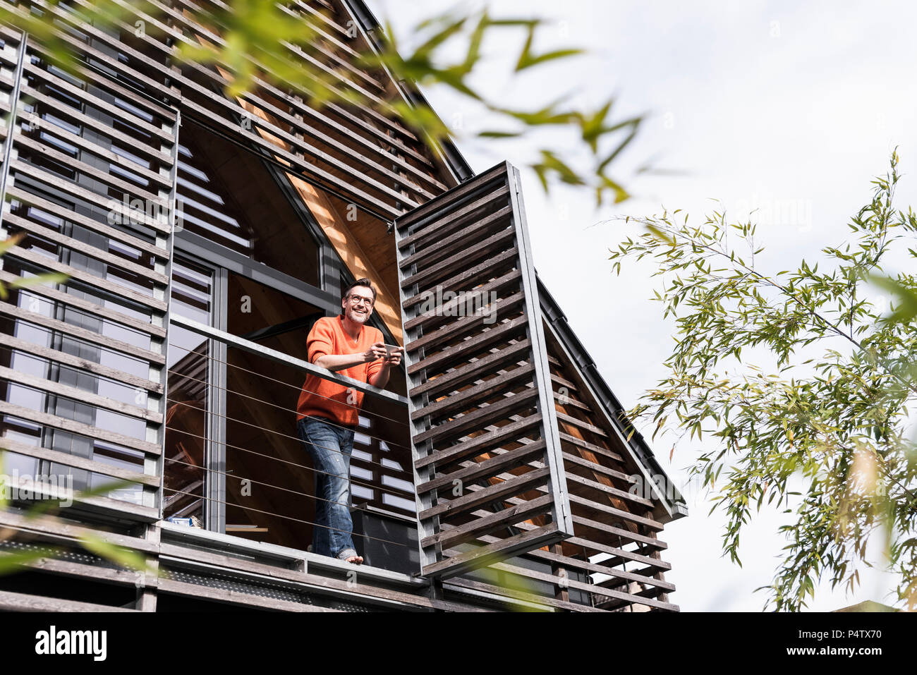 Homme debout sur smartphone avec balcon de sa maison à distance à Banque D'Images