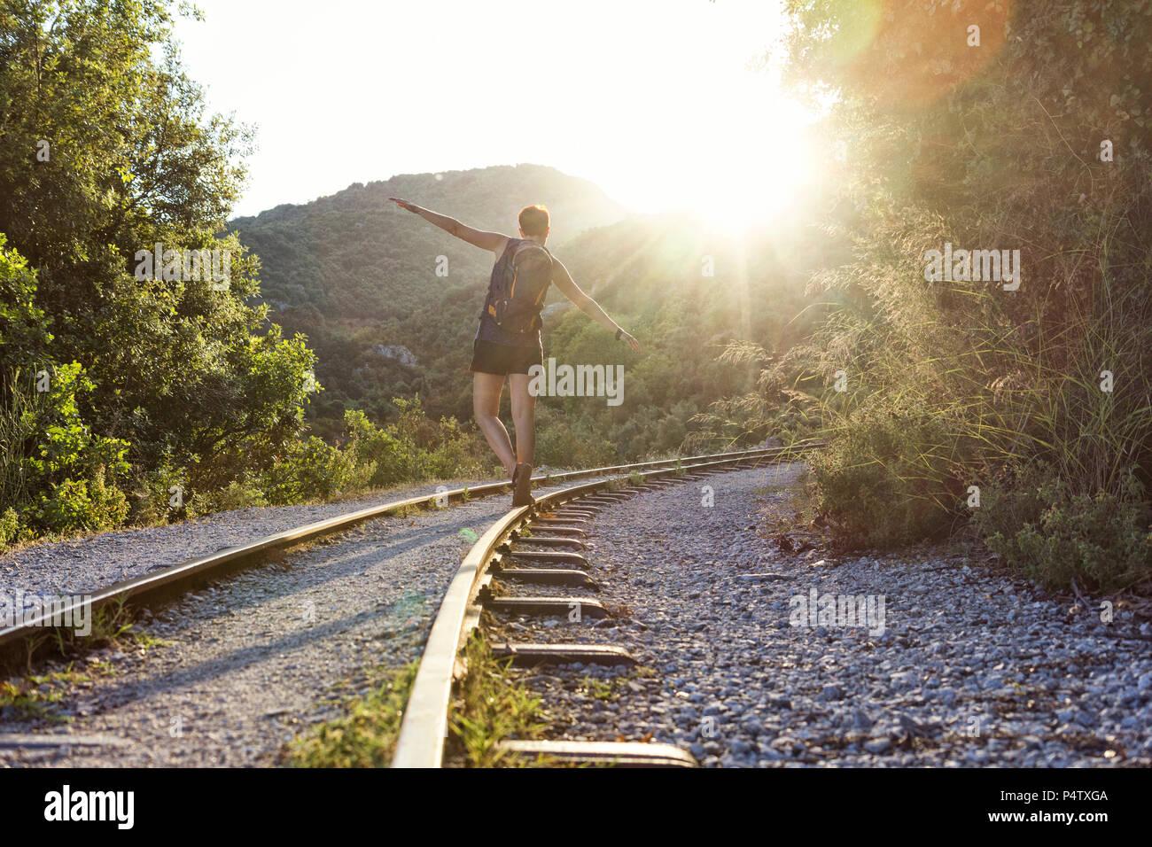 La Grèce, le Pilion, Milies, vue arrière de woman balancing le long de rails de chemin de fer à voie étroite au coucher du soleil Banque D'Images