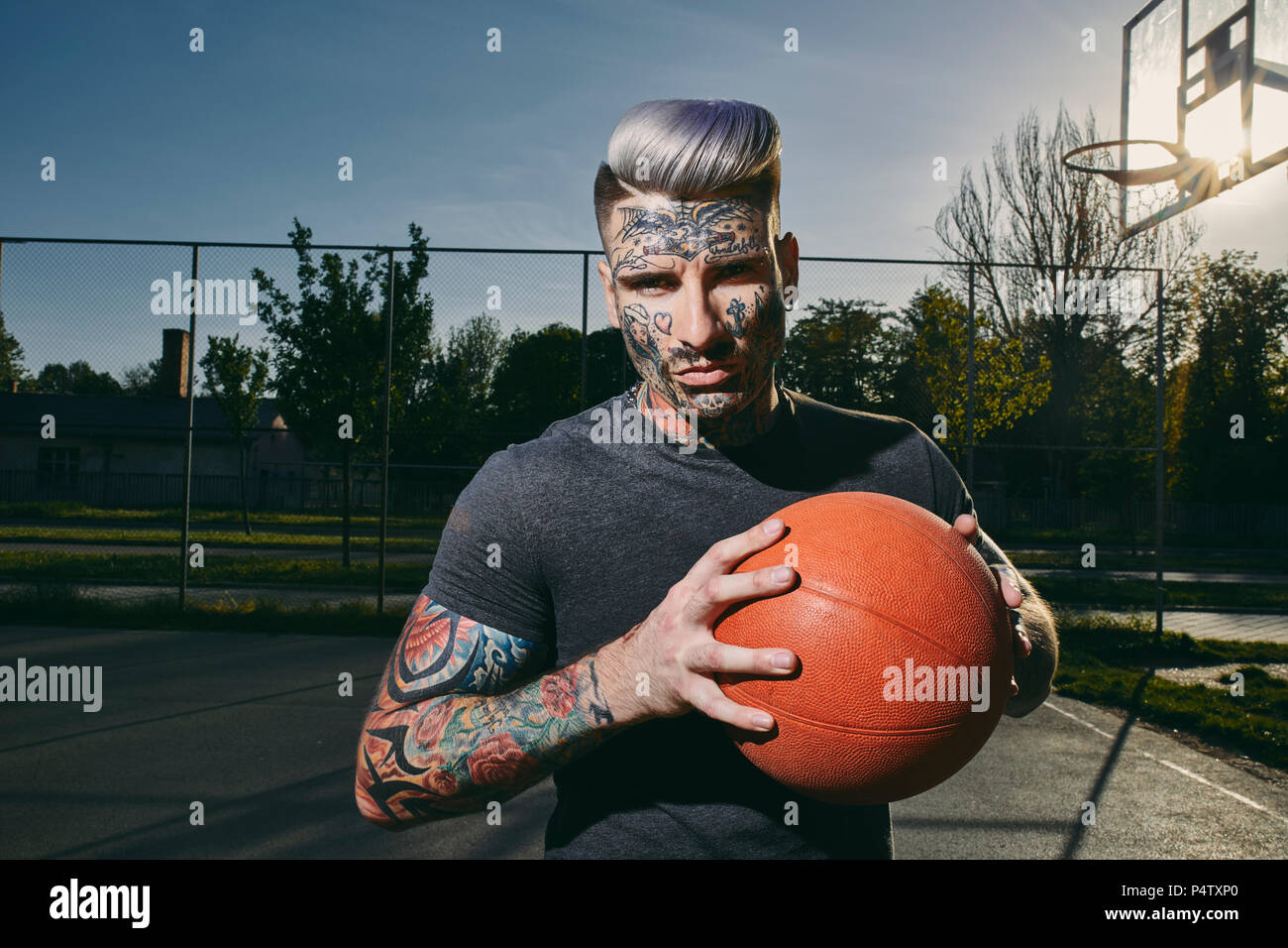 Portrait de jeune homme tatoué avec le basket-ball sur cour Banque D'Images