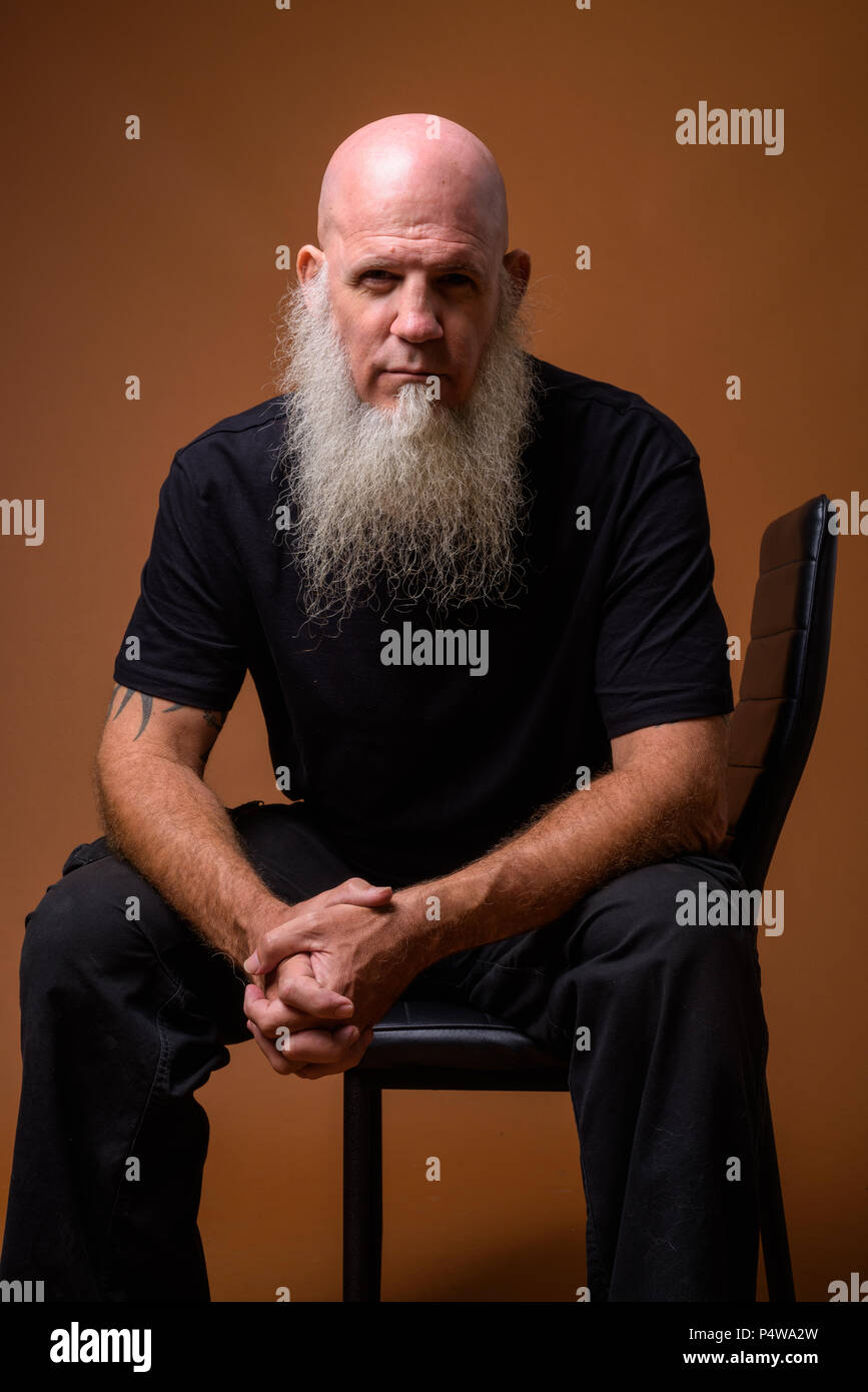 Homme chauve avec maturité longue barbe grise contre fond brun Banque D'Images