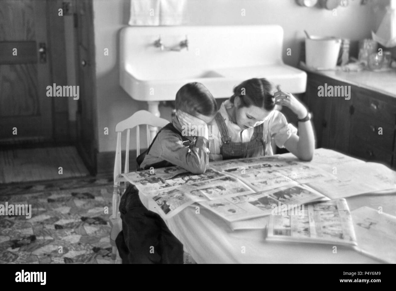 Enfants lisant le journal du dimanche, la famille de fermier, Dickens, Iowa, États-Unis, Russell Lee, États-Unis La réinstallation de l'Administration, Décembre 1936 Banque D'Images