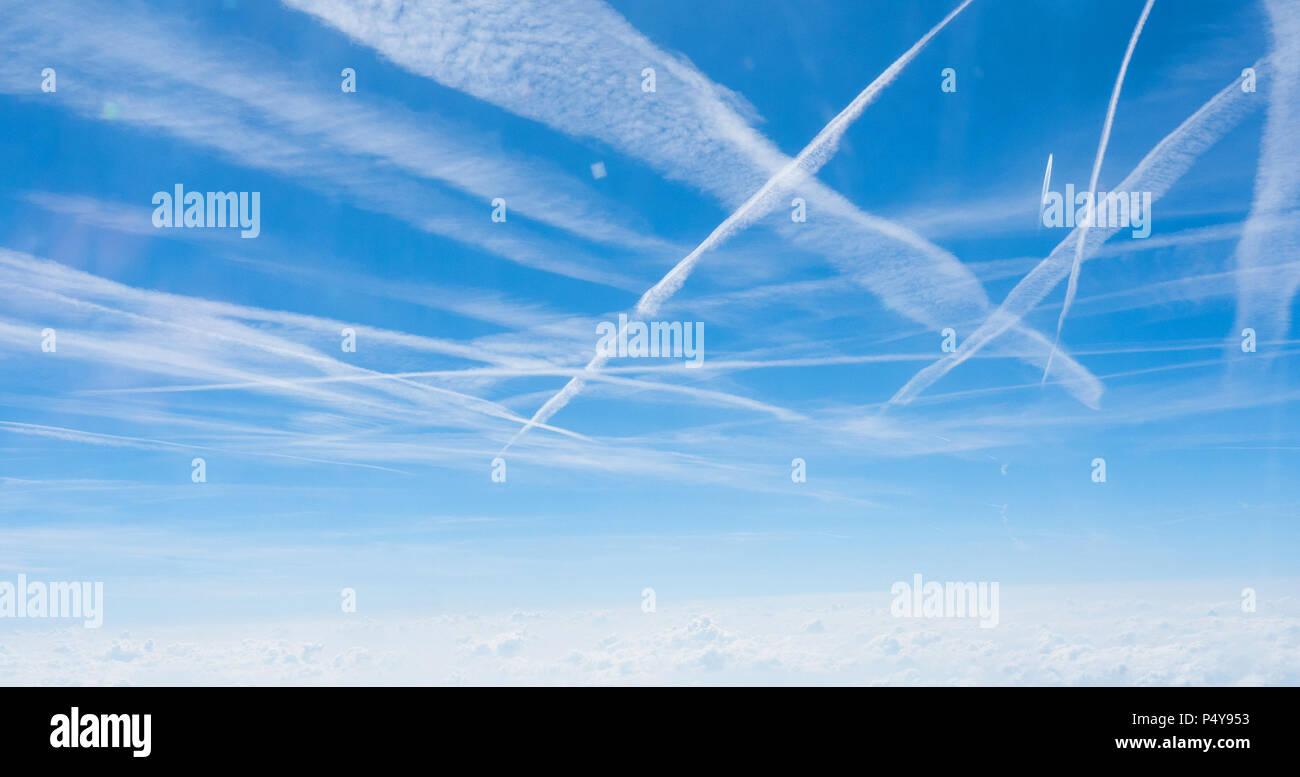 Plusieurs trainées de croiser dans le ciel au-dessus d'une couche de nuages au-dessus de l'Allemagne. Banque D'Images