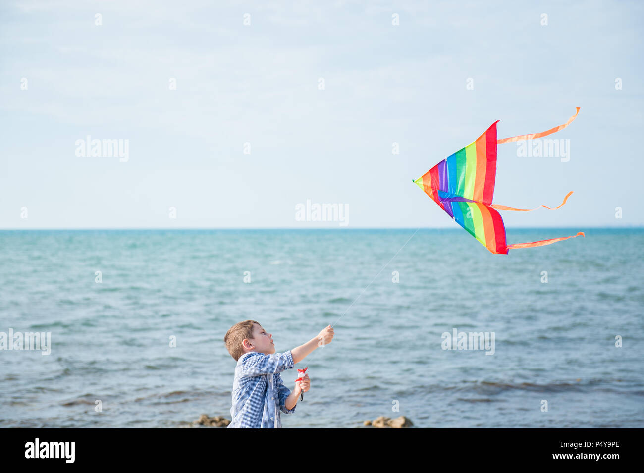 Enfant saine et active avec le vol de cerf-volant coloré sur ciel et mer piscine d'arrière-plan Banque D'Images