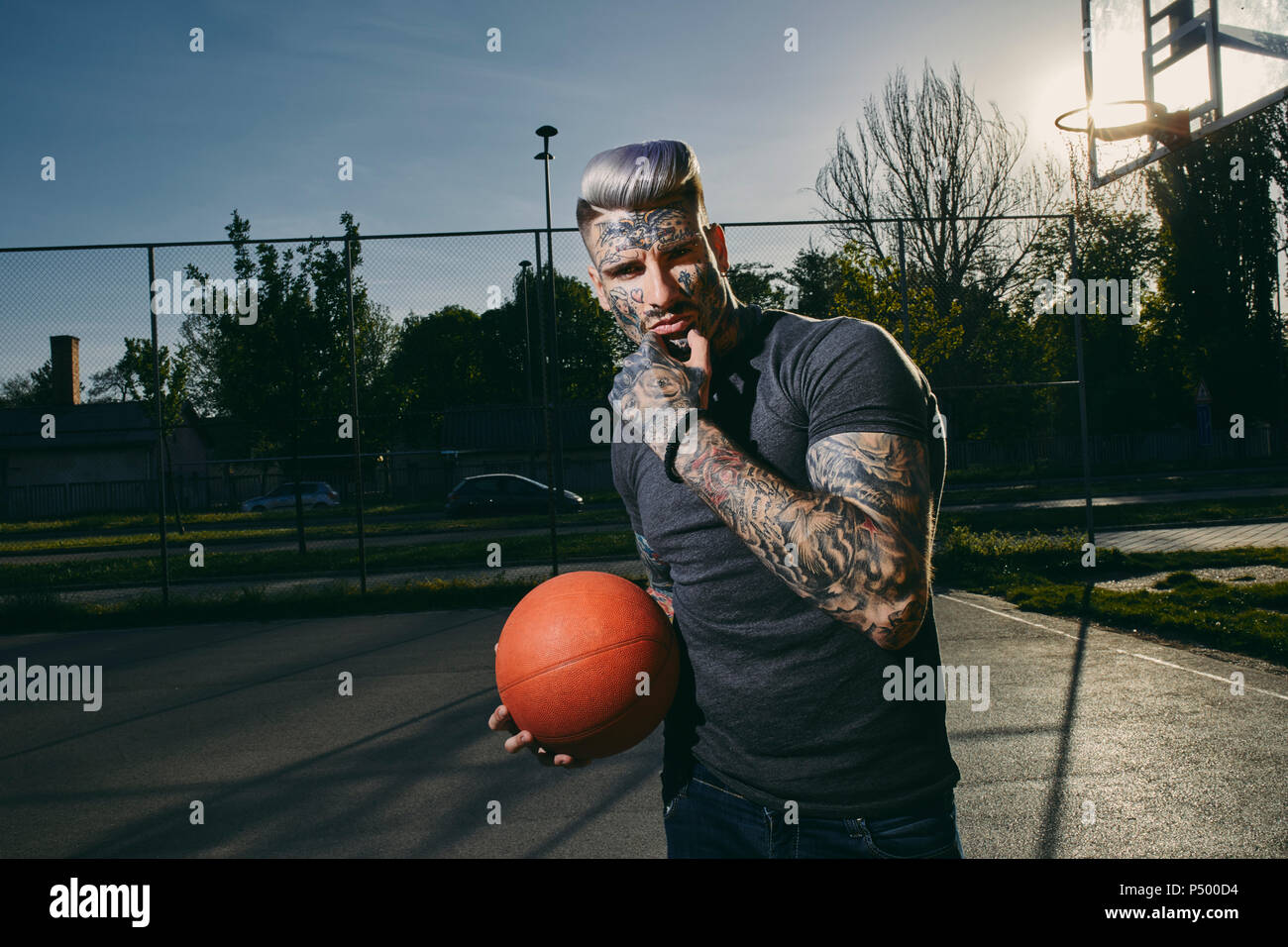 Portrait de jeune homme tatoué avec le basket-ball sur cour Banque D'Images