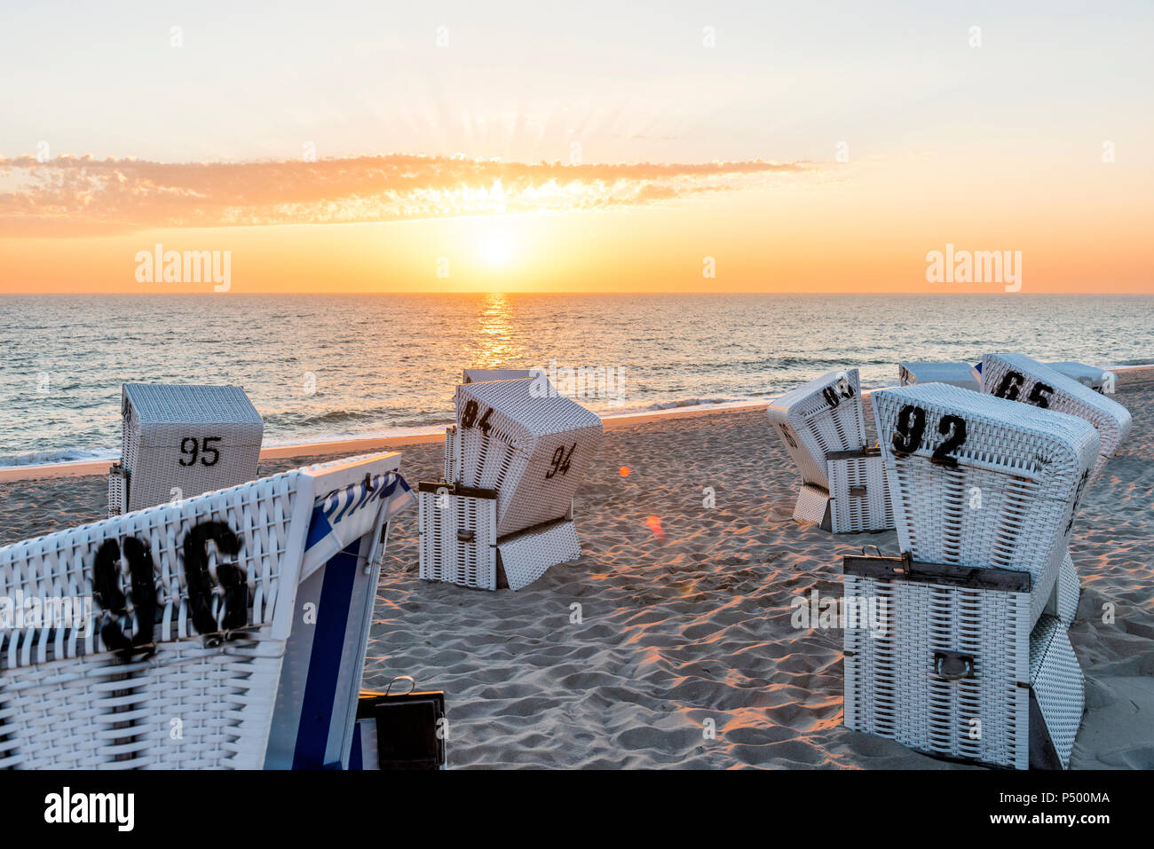 Allemagne, Schleswig-Holstein, Sylt, plage et à capuchon vide chaises de plage au coucher du soleil Banque D'Images