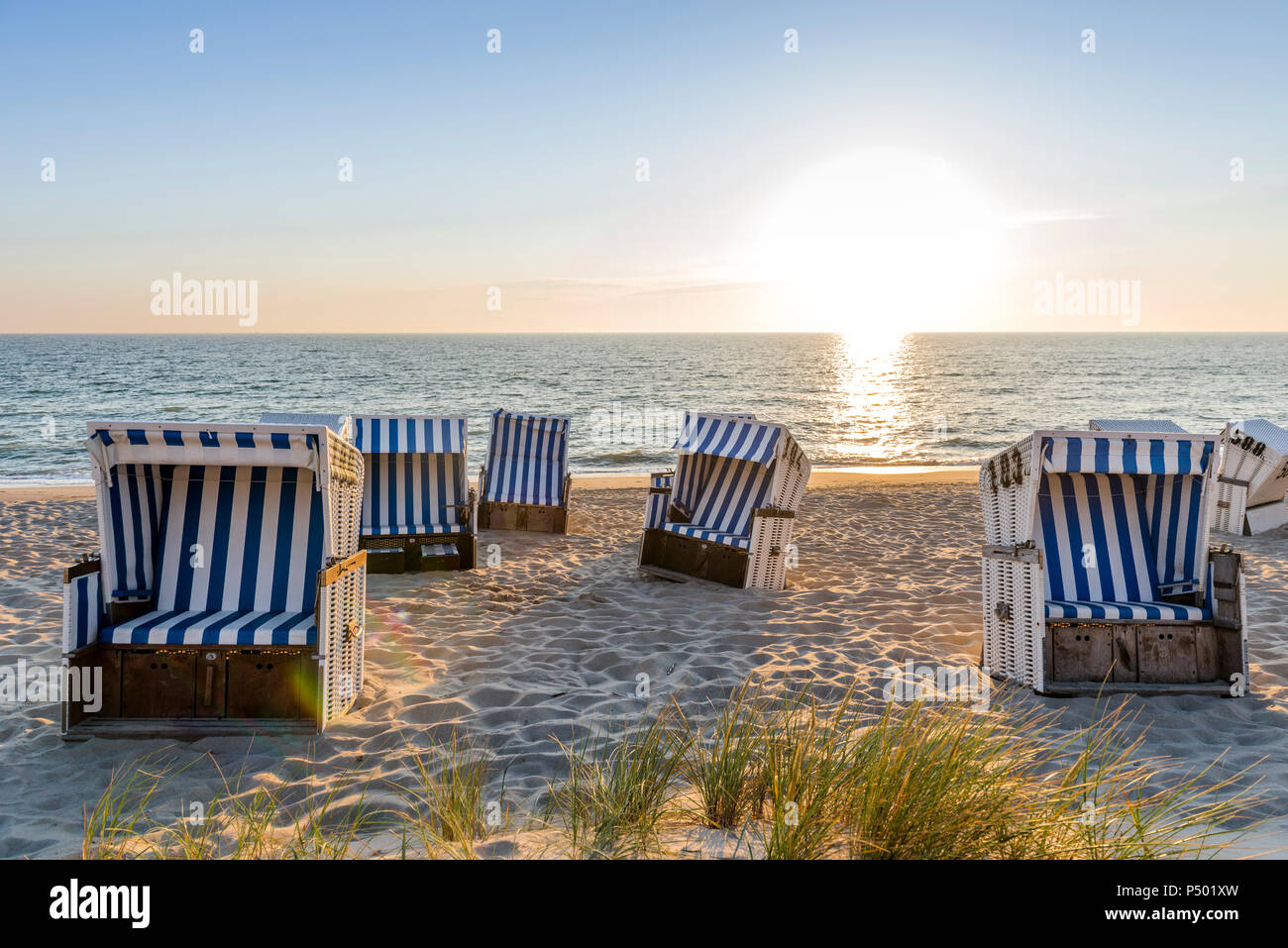 Allemagne, Schleswig-Holstein, Sylt, plage et à capuchon vide chaises de plage au coucher du soleil Banque D'Images