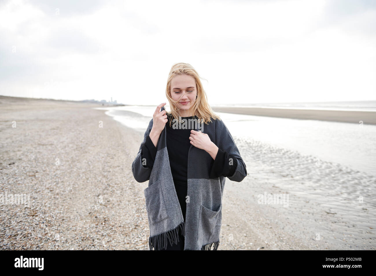 Pays-bas, blonde jeune femme portant veste grise sur la plage Banque D'Images