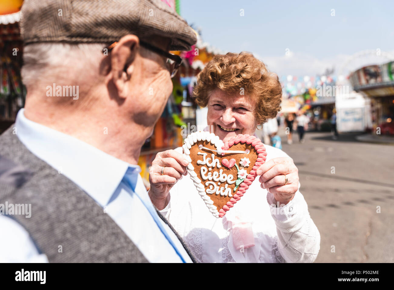 Portrait of senior man hasmiling présentant gingerbread heart on fair Banque D'Images