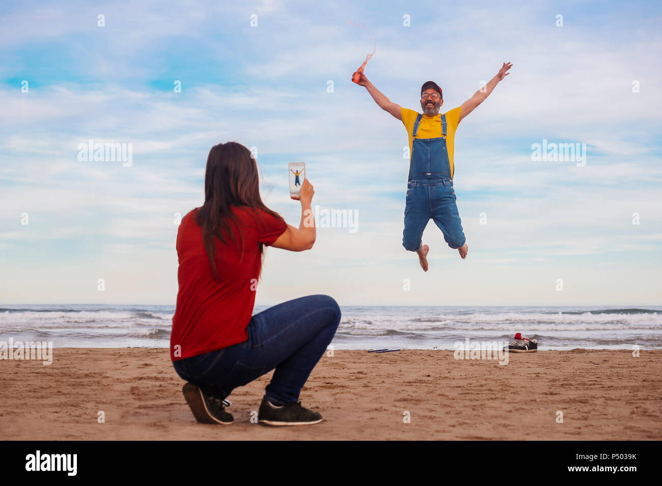 Woman taking photo smartphone d'homme heureux de sauter sur la plage Banque D'Images