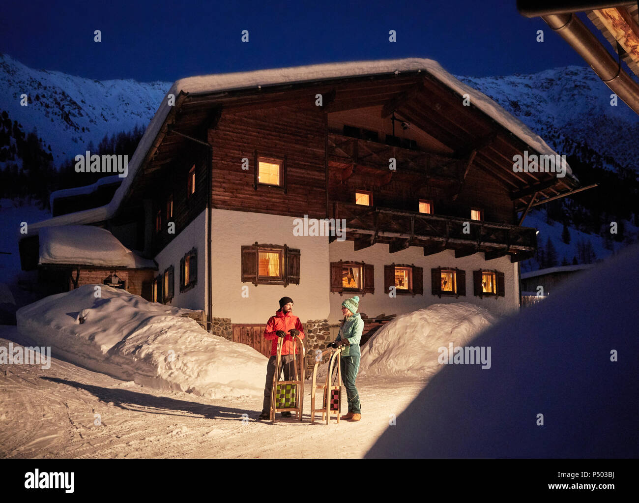 Couple avec traîneaux dans la neige paysage avec maison rustique dans la nuit Banque D'Images