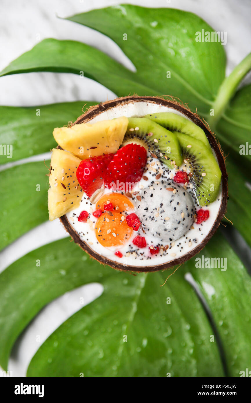 Bol avec de la noix de coco fruits variuos, yaourt nature et les graines on leaf Banque D'Images