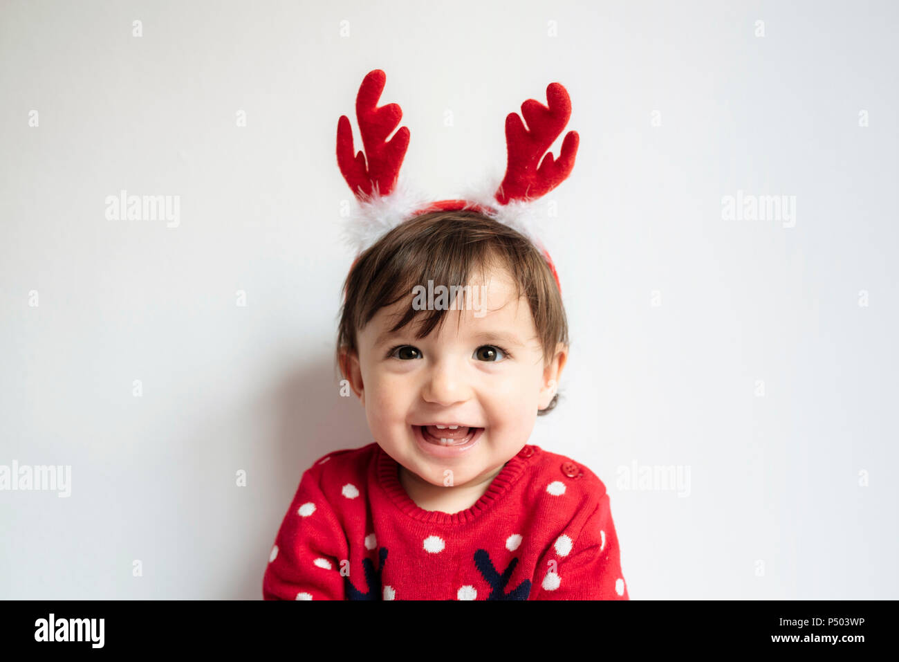 Portrait of laughing baby girl wearing reindeer antlers headband Banque D'Images