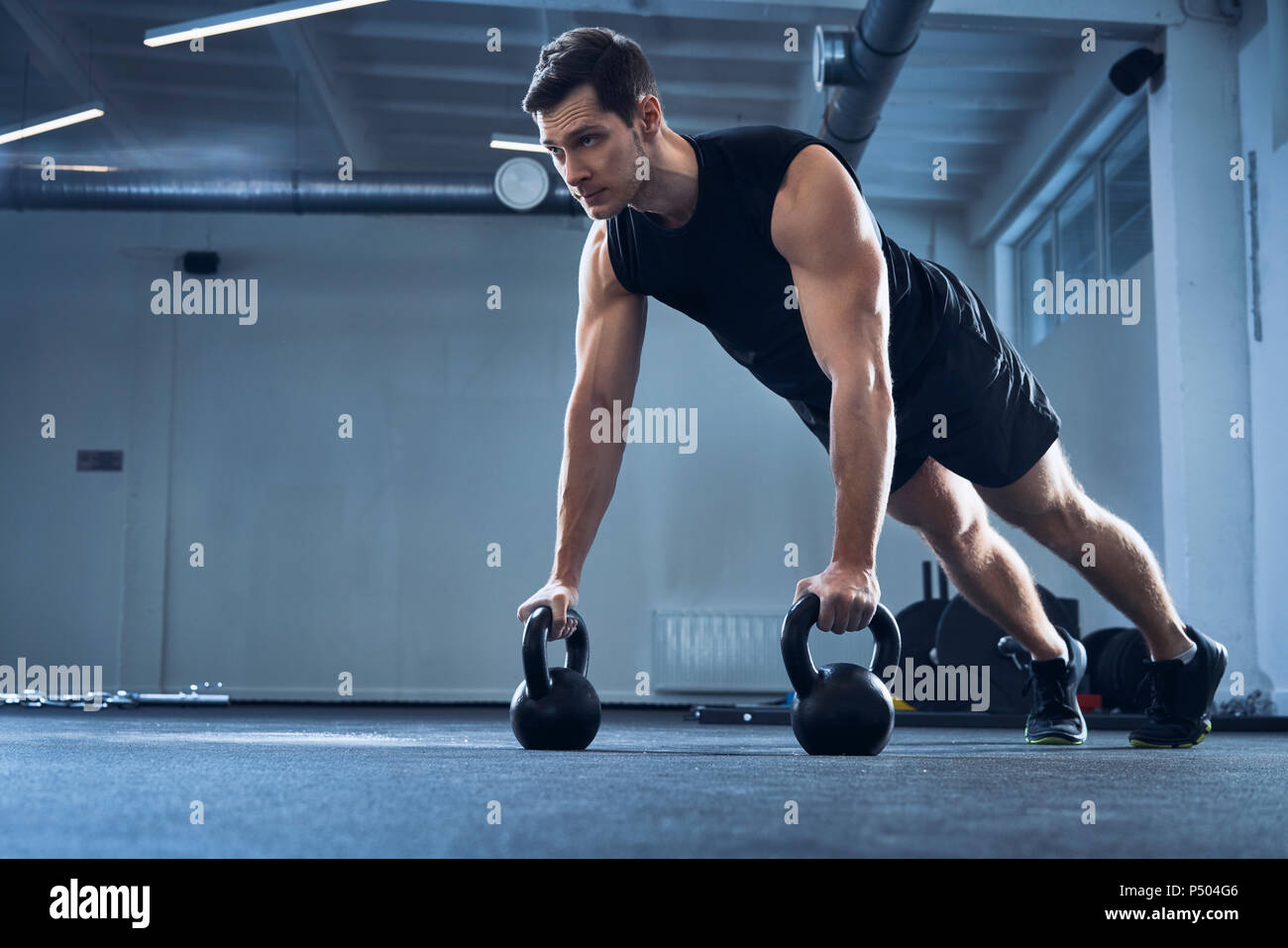 Man doing pushups sur kettlebells at gym Banque D'Images