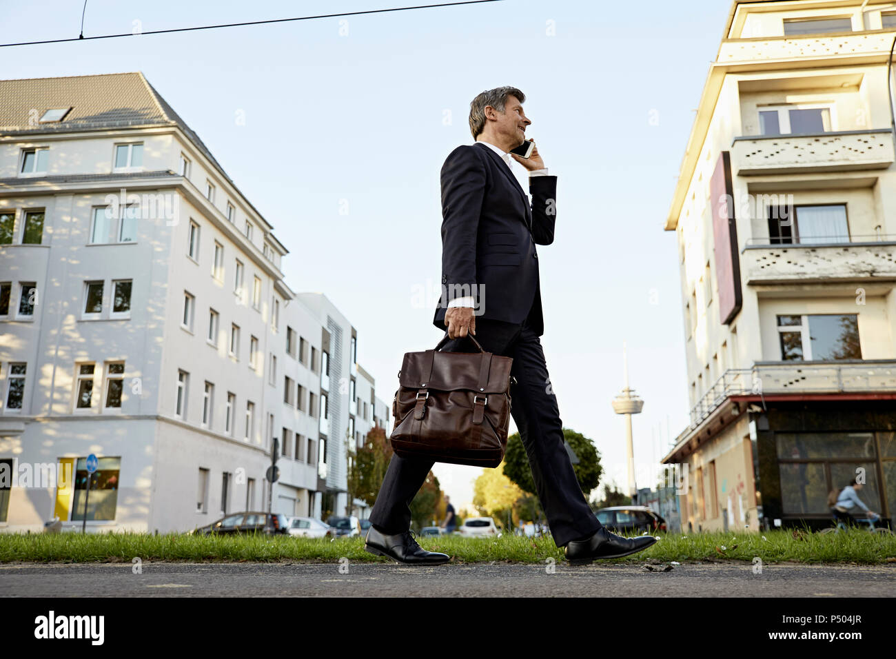 Mature businessman walking and using smartphone dans la ville Banque D'Images