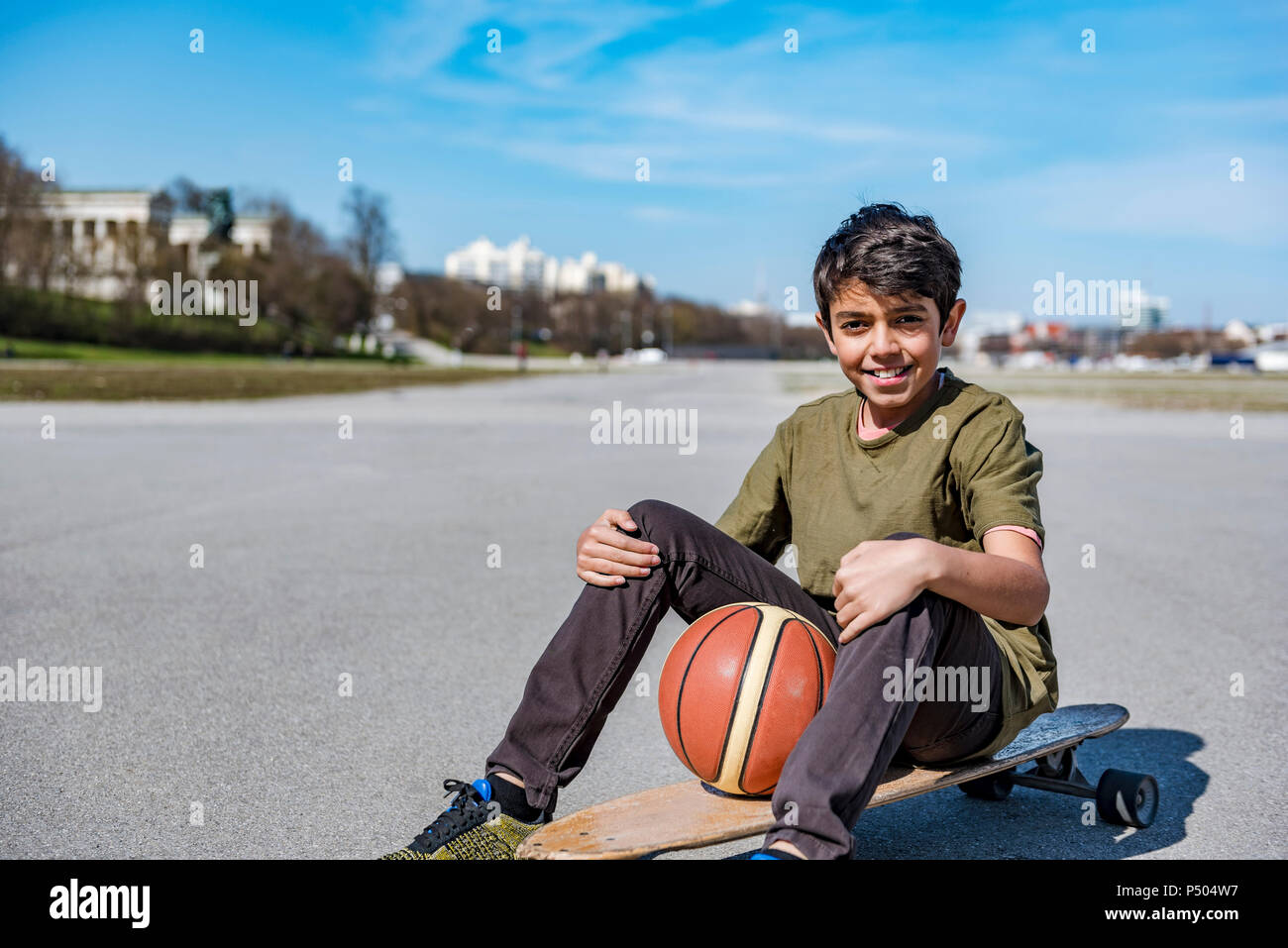 Portrait of smiling boy with longboard et de basket-ball extérieur Banque D'Images