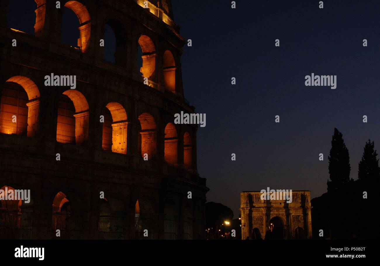 L'Italie. Rome. Le Colisée (Coliseum) ou Flavian Amphitheater. La construction elliptique construits en béton et en pierre. 1er siècle A.C. Vue nocturne. À l'arrière-plan, l'Arc de Constantin. Banque D'Images