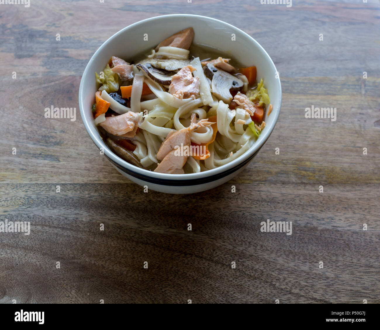 Soupe de nouilles de riz avec des légumes et du saumon, gros plan et Vue de dessus, sur fond de table en bois, prêt à manger Banque D'Images