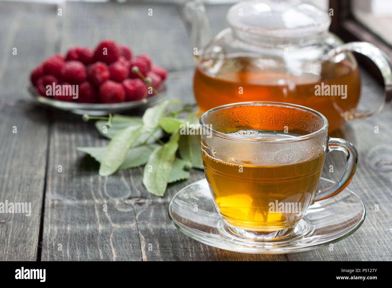 La framboise et le thé vert de un linden sur une table en bois Banque D'Images