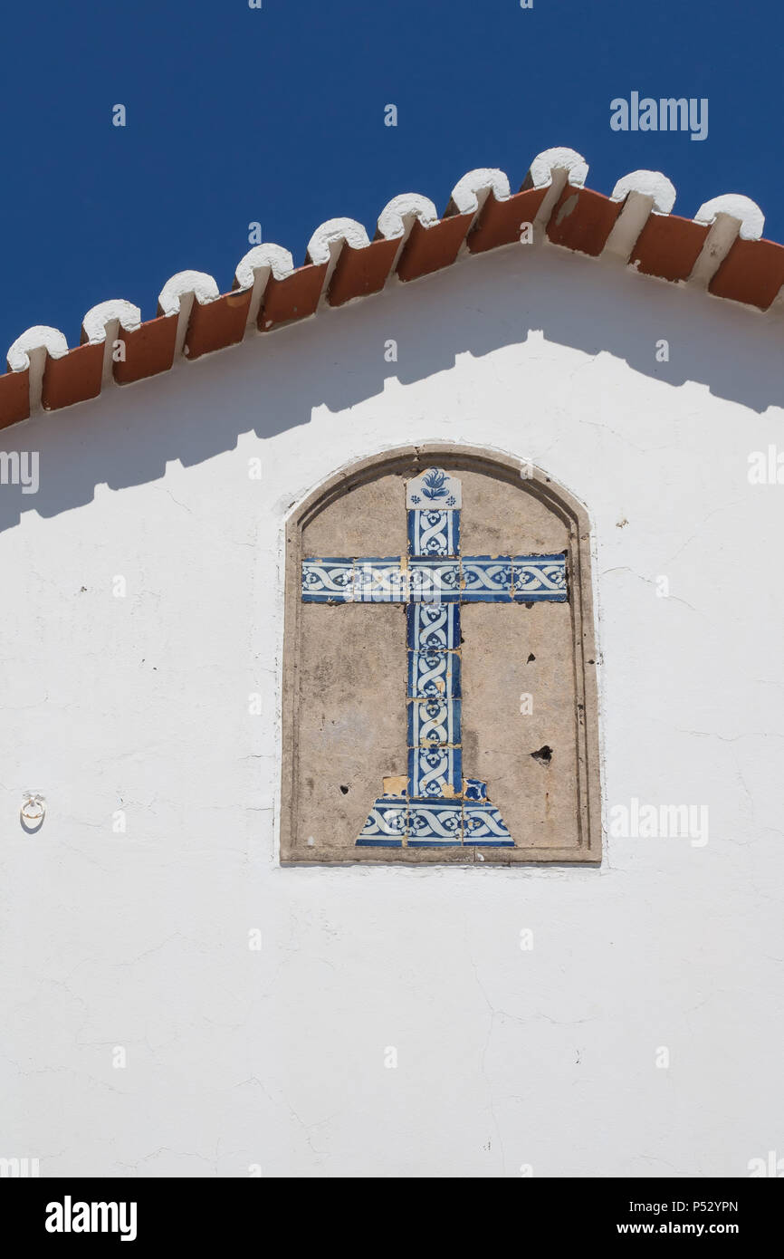 Côté blanc mur d'une église Nossa Senhora do Rocha avec une croix faite de carreaux de céramique traditionnels - azulejos. Bord du toit. Ciel bleu. P Banque D'Images