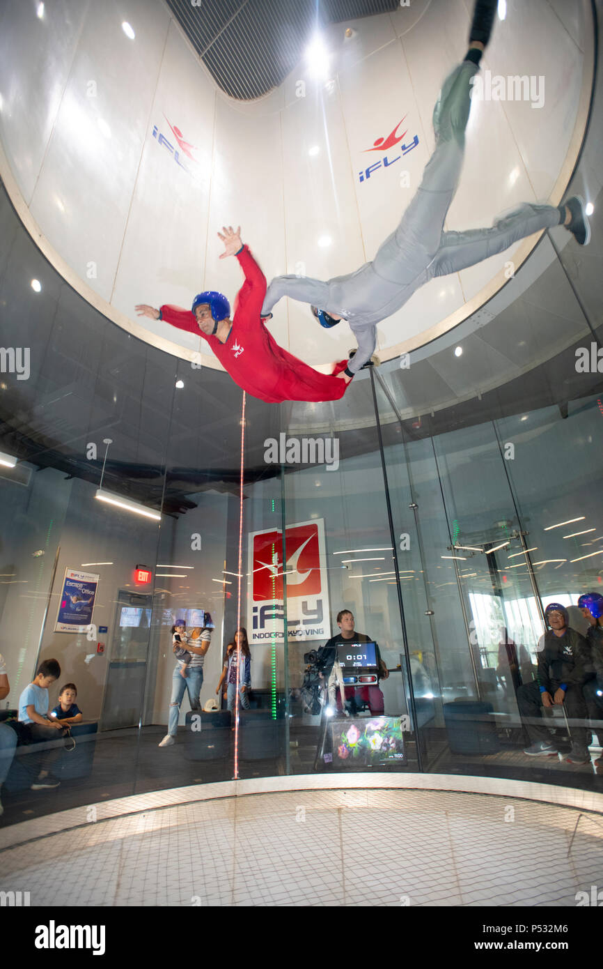 Soufflerie iFly indoor skydiving donnant au participant le sentiment de la chute libre sans poids sur la photo d'un instructeur et de l'enfant Banque D'Images