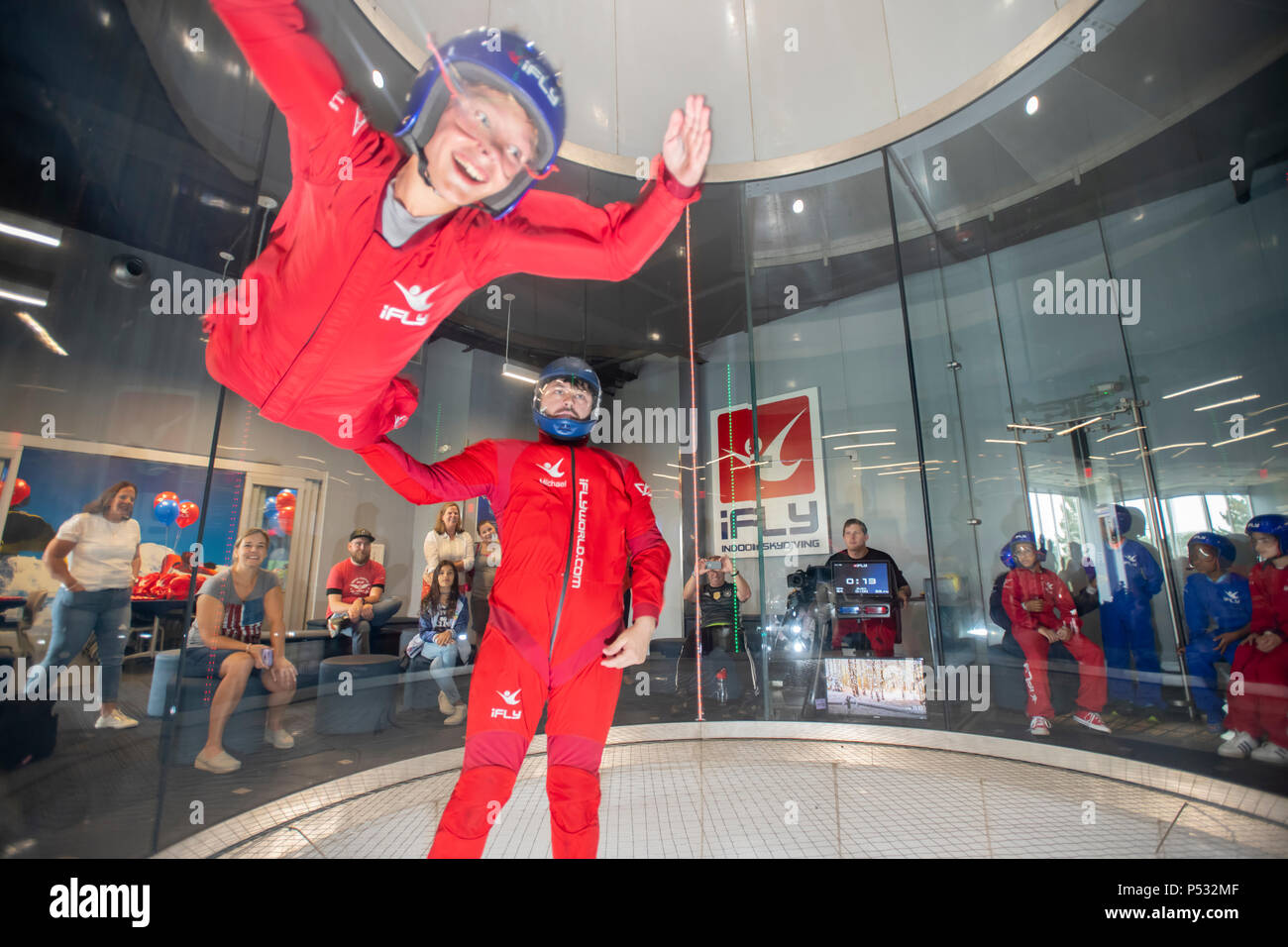 Soufflerie iFly indoor skydiving donnant au participant le sentiment de la chute libre sans poids sur la photo d'un instructeur et de l'enfant Banque D'Images