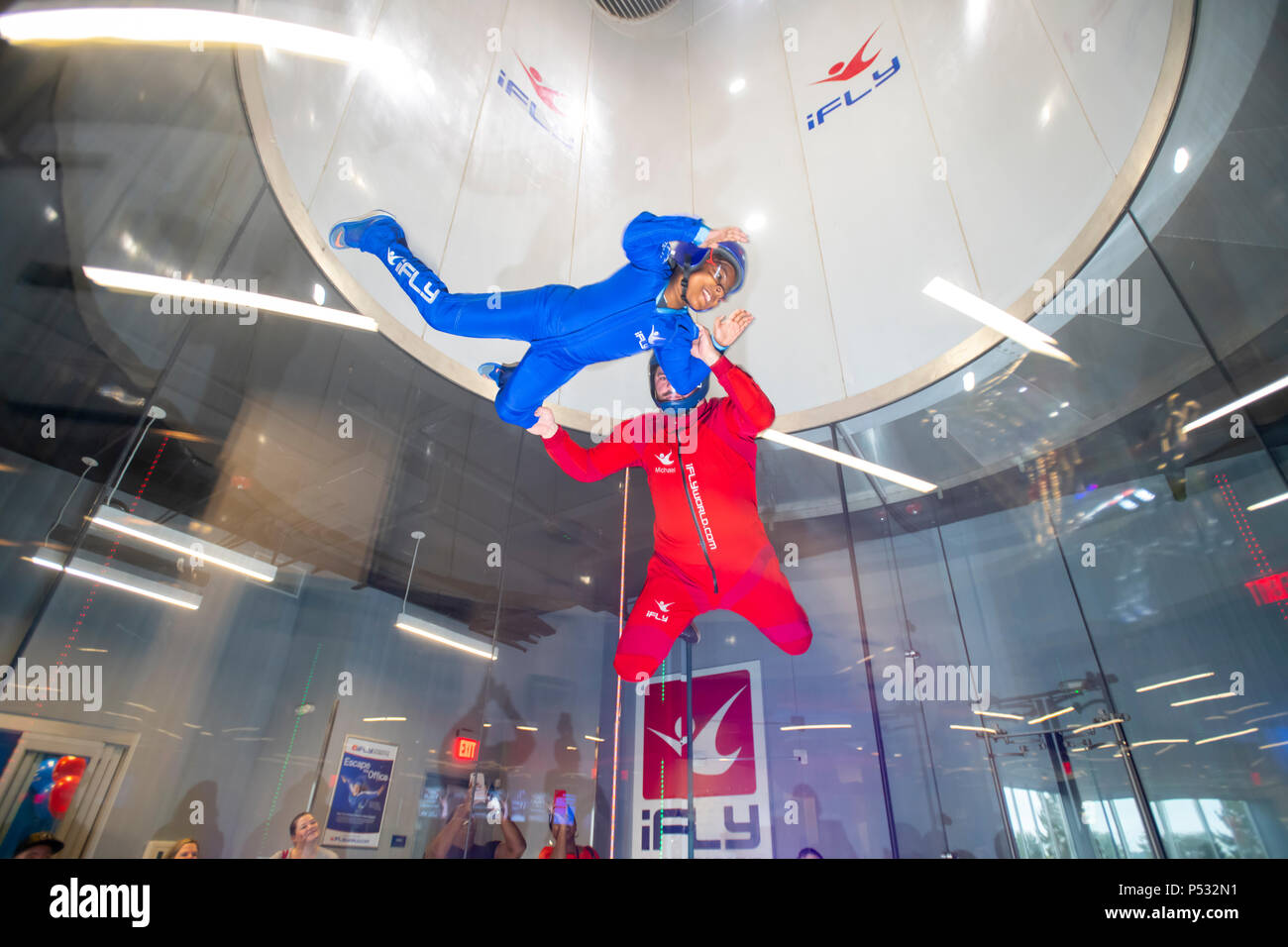 Soufflerie iFly indoor skydiving donnant au participant le sentiment de la chute libre sans poids sur la photo d'un instructeur et de l'enfant Banque D'Images