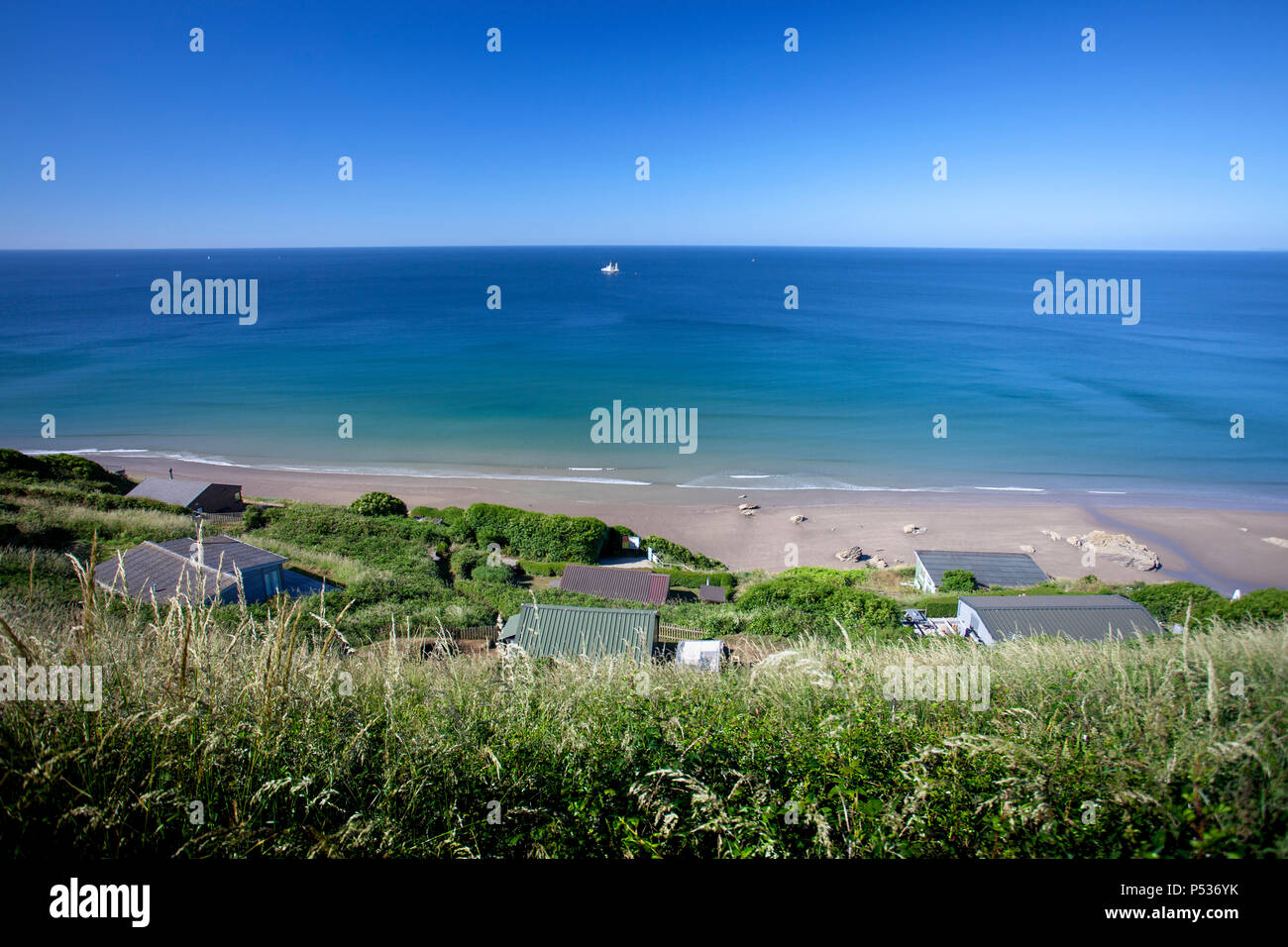 Une belle vue de Tregonhawke falaise sur location de vacances à la mer turquoise ci-dessous sur une chaude journée d'été, de Whitsand Bay, Cornwall, UK Banque D'Images