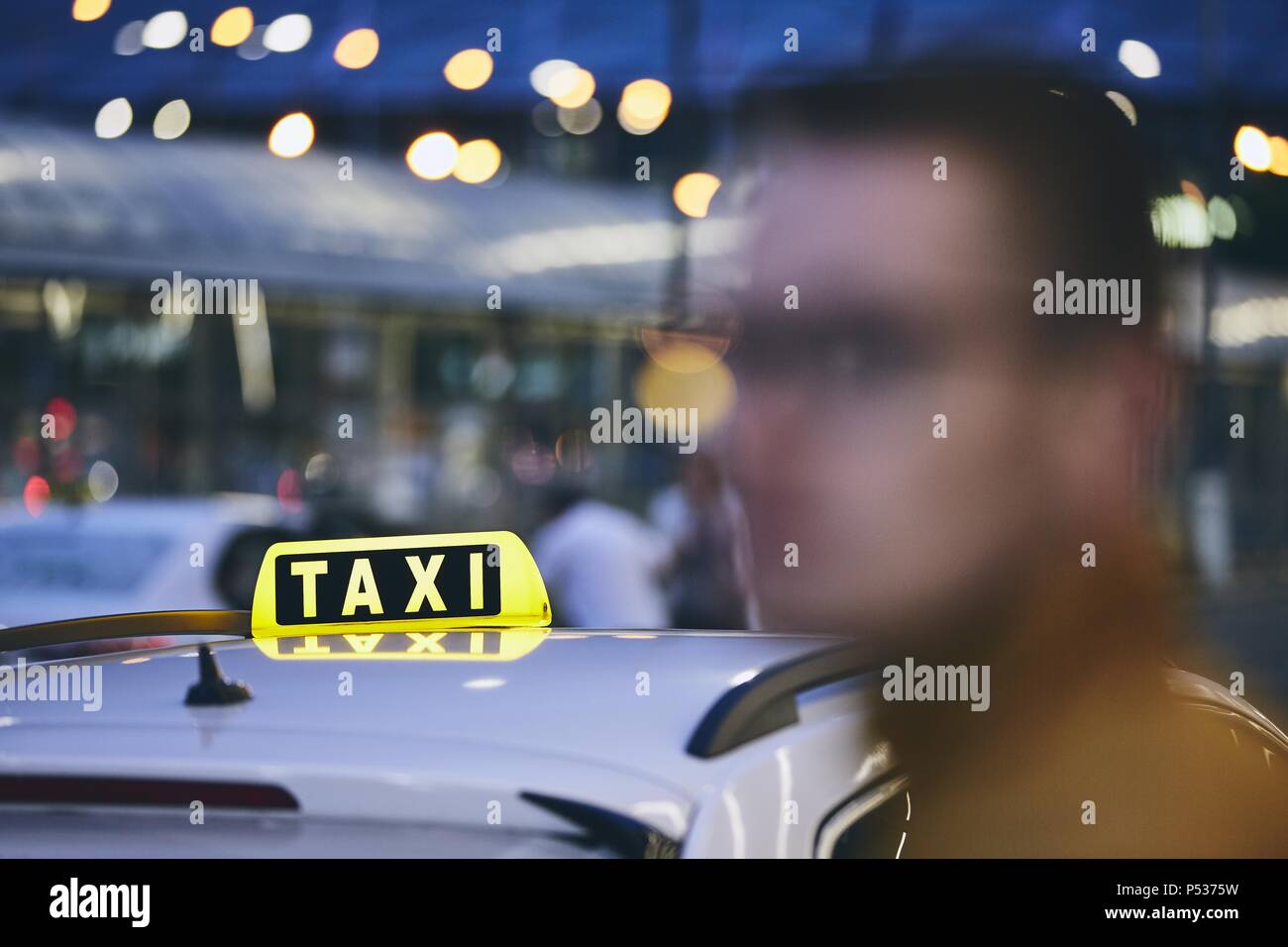 Jeune homme en attente de taxi dans la ville rue la nuit. Selective focus sur le signe de taxi. Banque D'Images