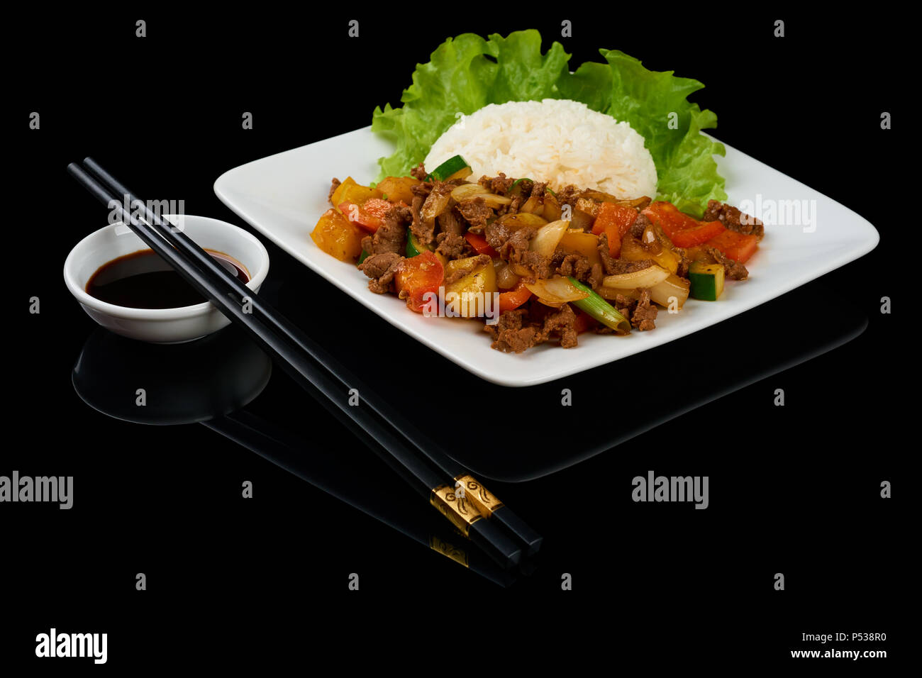 Plat vietnamien Bo Luc Lac (faire sauter les dés de boeuf) est un boeuf en cubes sauté aux concombres, tomates, oignons rouges, poivre et sauce de soja. Isolated on black Banque D'Images