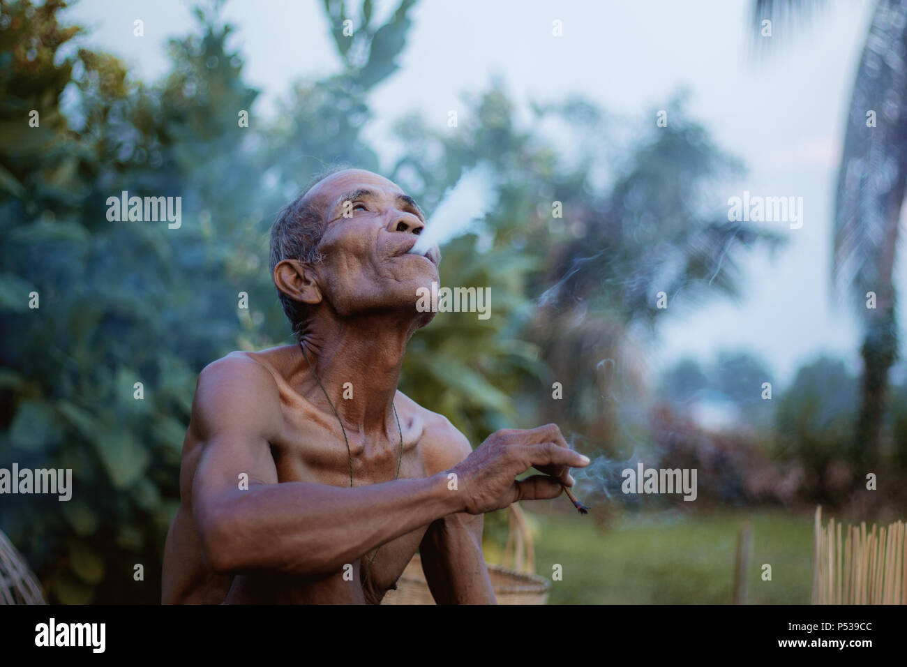 Vieil homme fume dans la campagne. Banque D'Images
