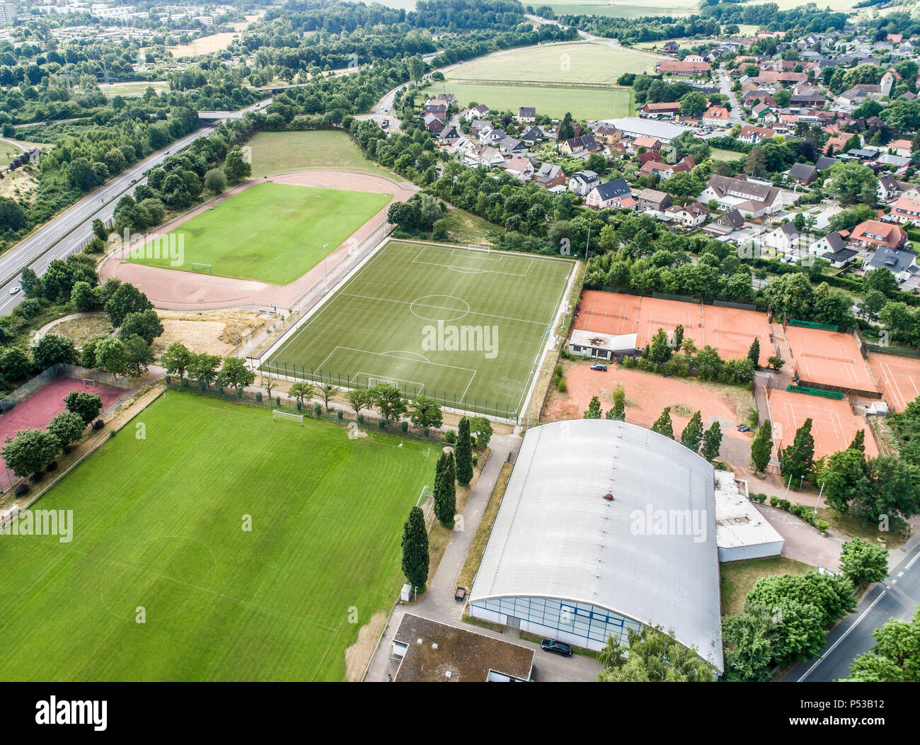 Court de tennis et de tennis intérieurs sur le bord d'un village de banlieue à côté de champs et prairies à proximité d'une autoroute Banque D'Images