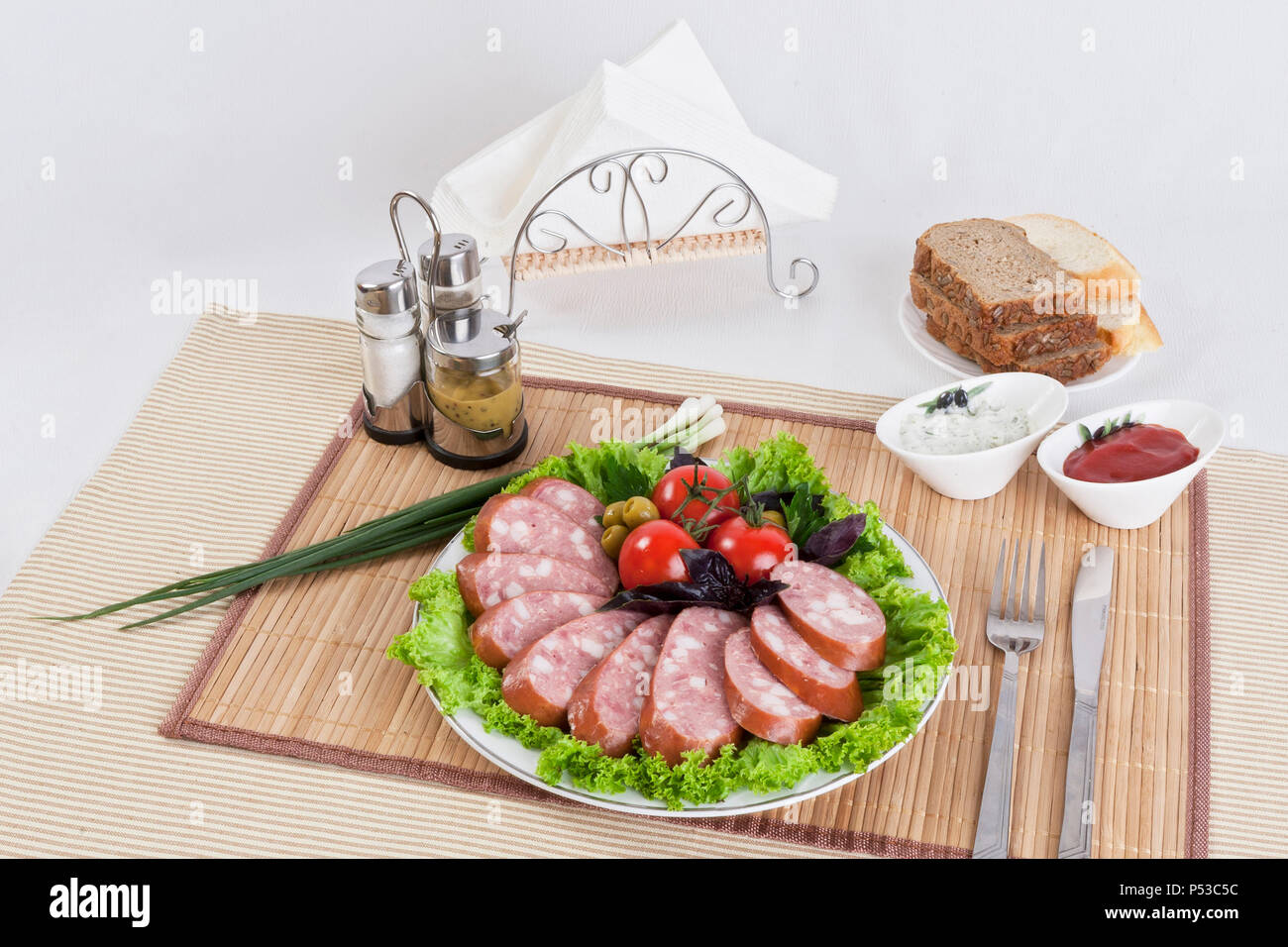 Saucisse fumée avec tomates et feuilles de laitue sur une assiette. Peut être utilisé dans la publicité et dans le développement de sites. Banque D'Images