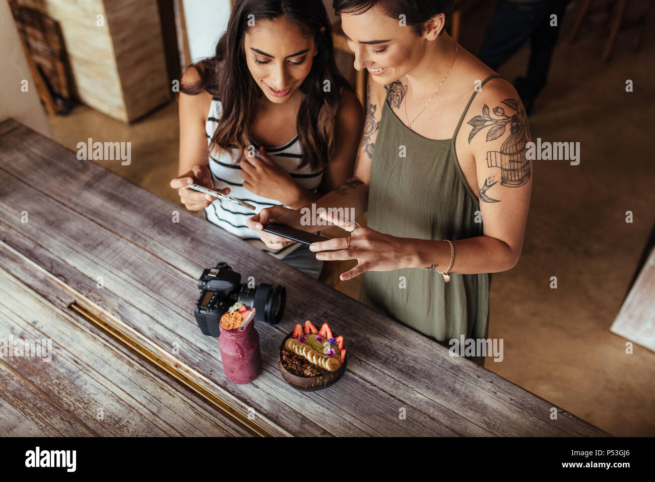 Les blogueurs alimentaire prise de photos pour leur blog en utilisant les téléphones mobiles. Photos de tournage blogueurs femmes coupe de fruits et jar smoothie placés le long d'une Banque D'Images