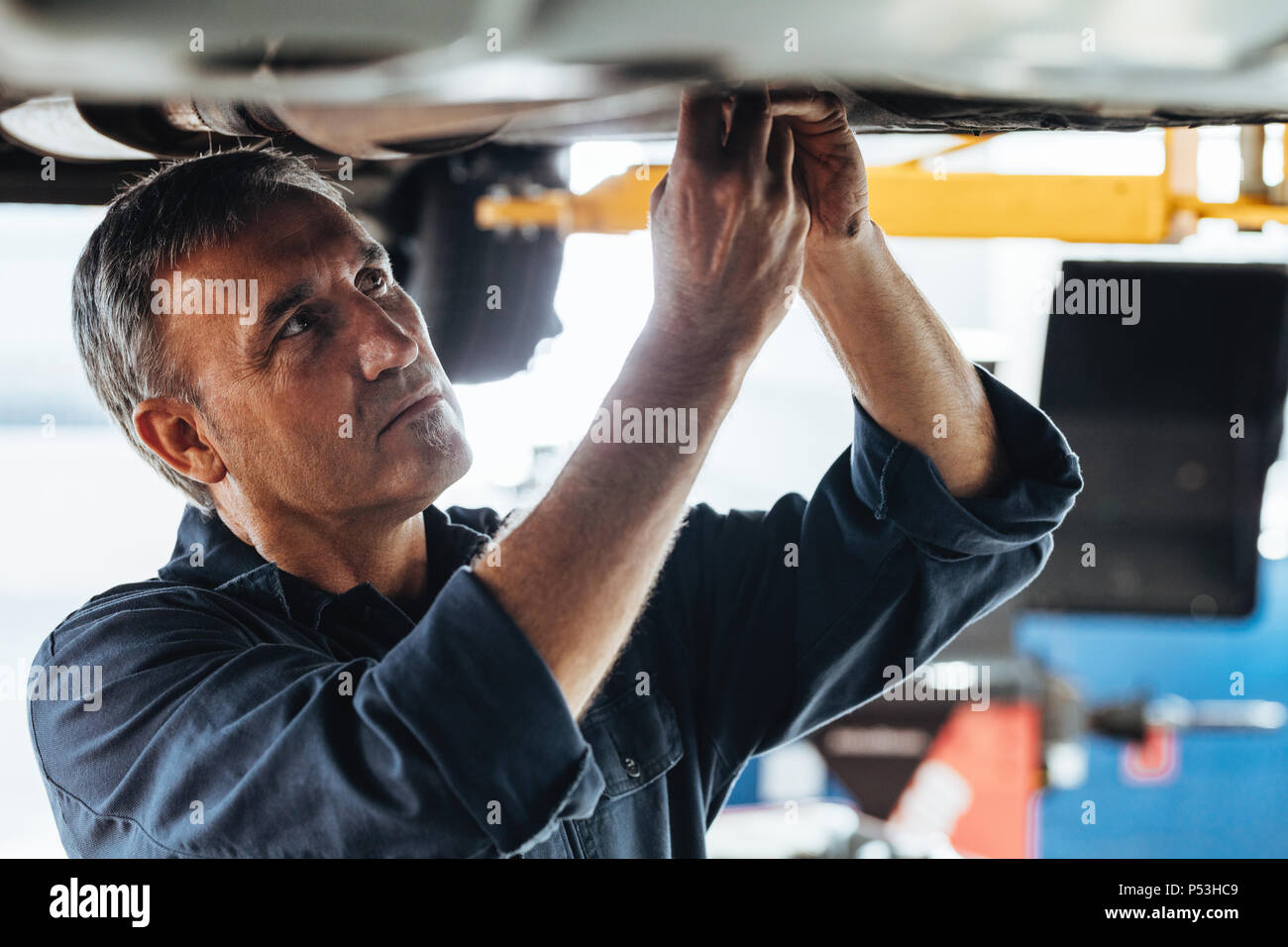 Mécanicien de voiture réparation d'une voiture à levée garage. Les hommes de réparation Auto réparation d'une voiture en station-service. Banque D'Images