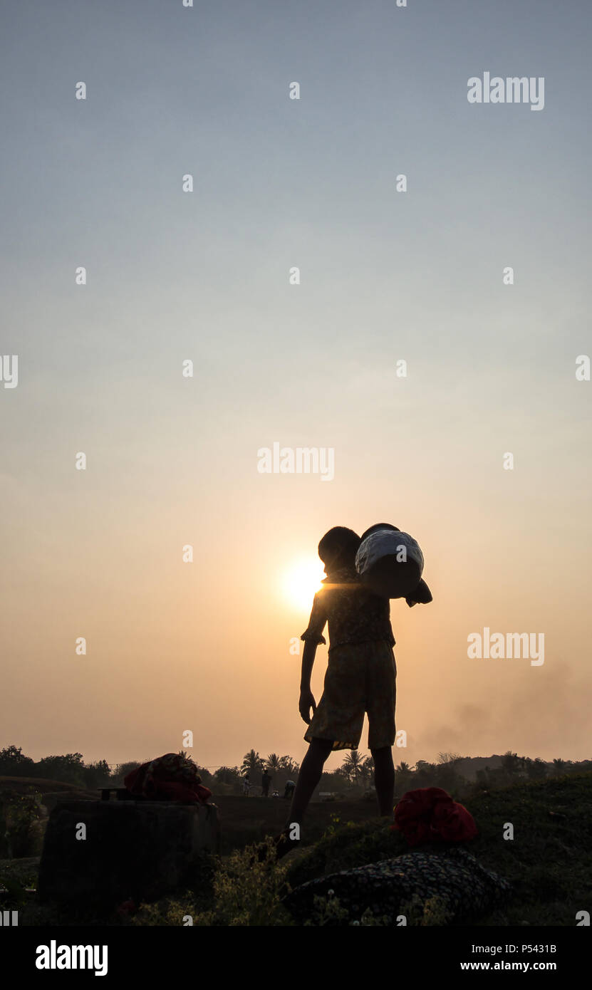 Un garçon de l'eau pot dans l'heure du coucher du soleil, Mrauk U Myanmar Banque D'Images