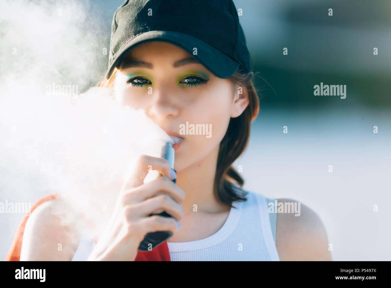 Jolie jeune fille asiatique vape portables populaires,gadget vaping  device.Happy brunette fille vaper avec e-cig.Portrait de fumeur modèle  féminin avec ec électronique Photo Stock