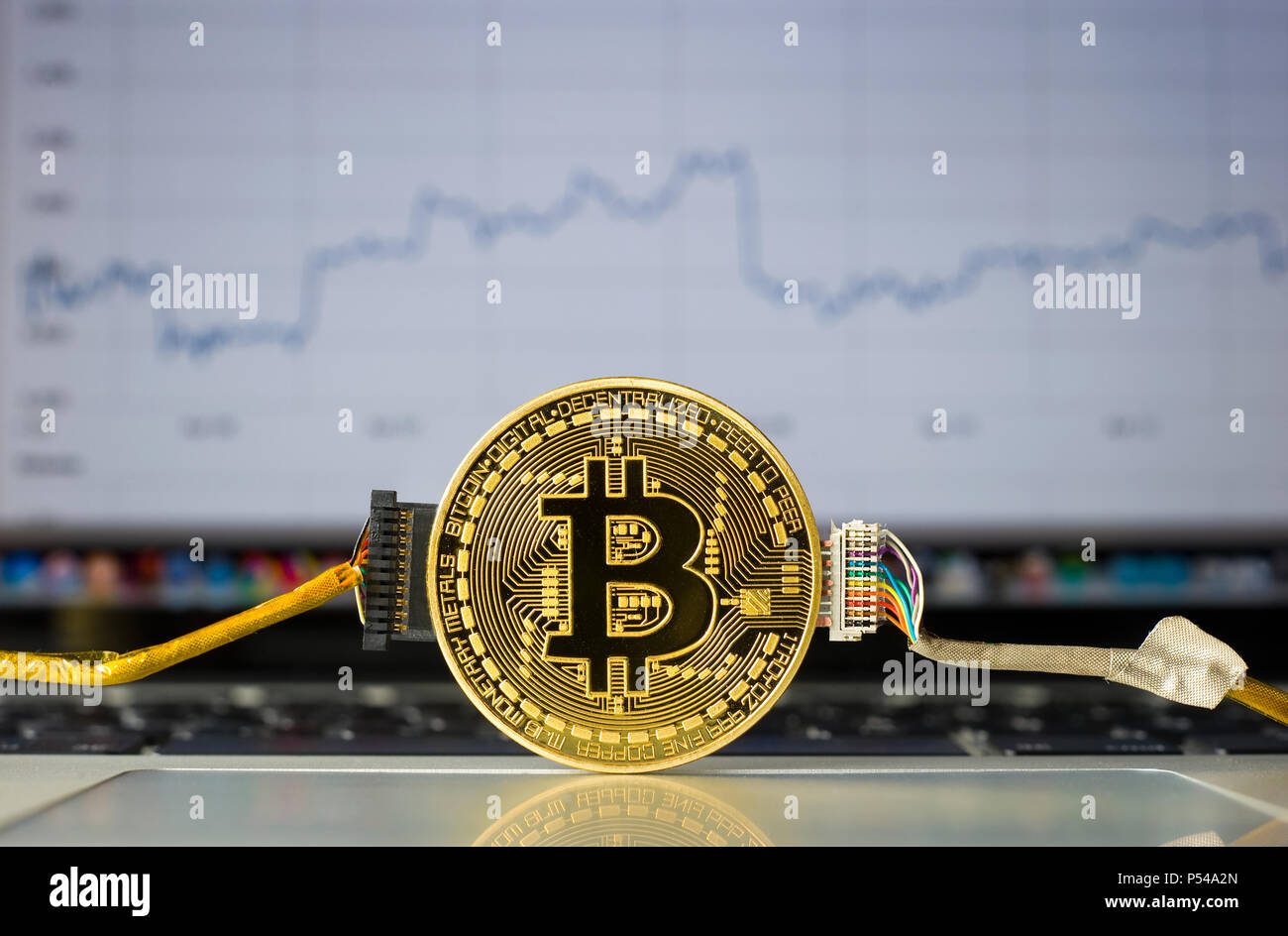 Bitcoin câblé sur un ordinateur portable en face d'une tendance de prix graffic sur l'écran. Banque D'Images