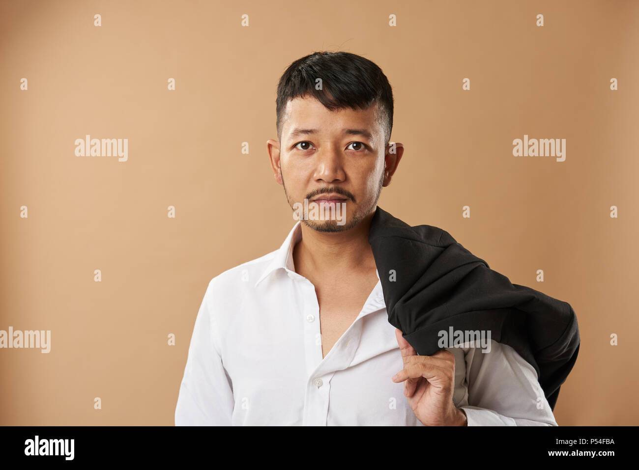 Young Asian man office worker eith jacket sur l'épaule isolé sur backgroundv beige Banque D'Images