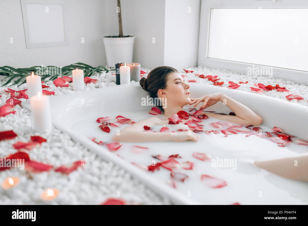Belle Dame couché dans la baignoire avec de la mousse et décoré avec des  pétales de rose. D'une détente complète dans la salle de bains Photo Stock  - Alamy