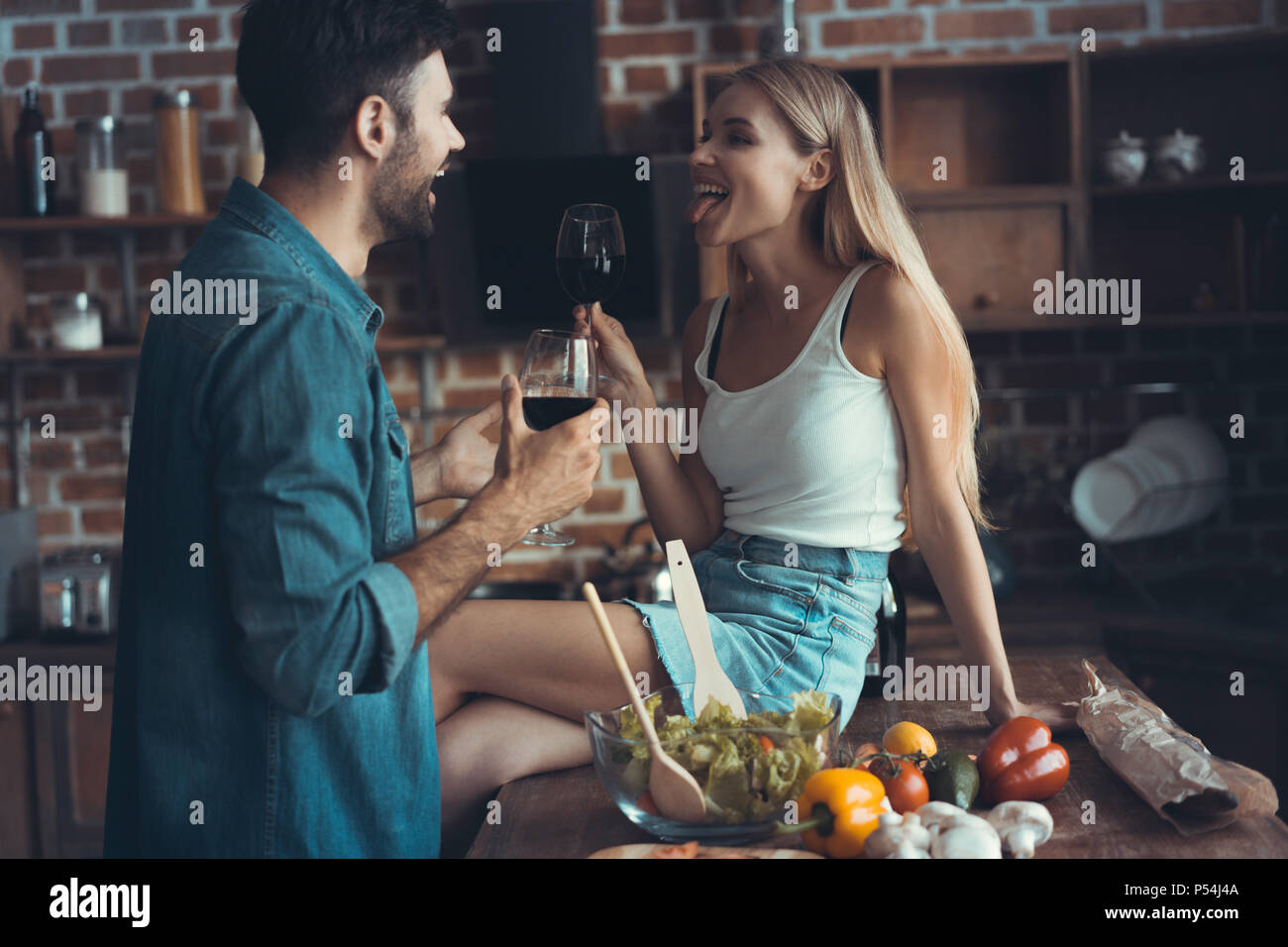 Beau jeune couple est de boire du vin et souriant pendant la cuisson dans la cuisine à la maison Banque D'Images