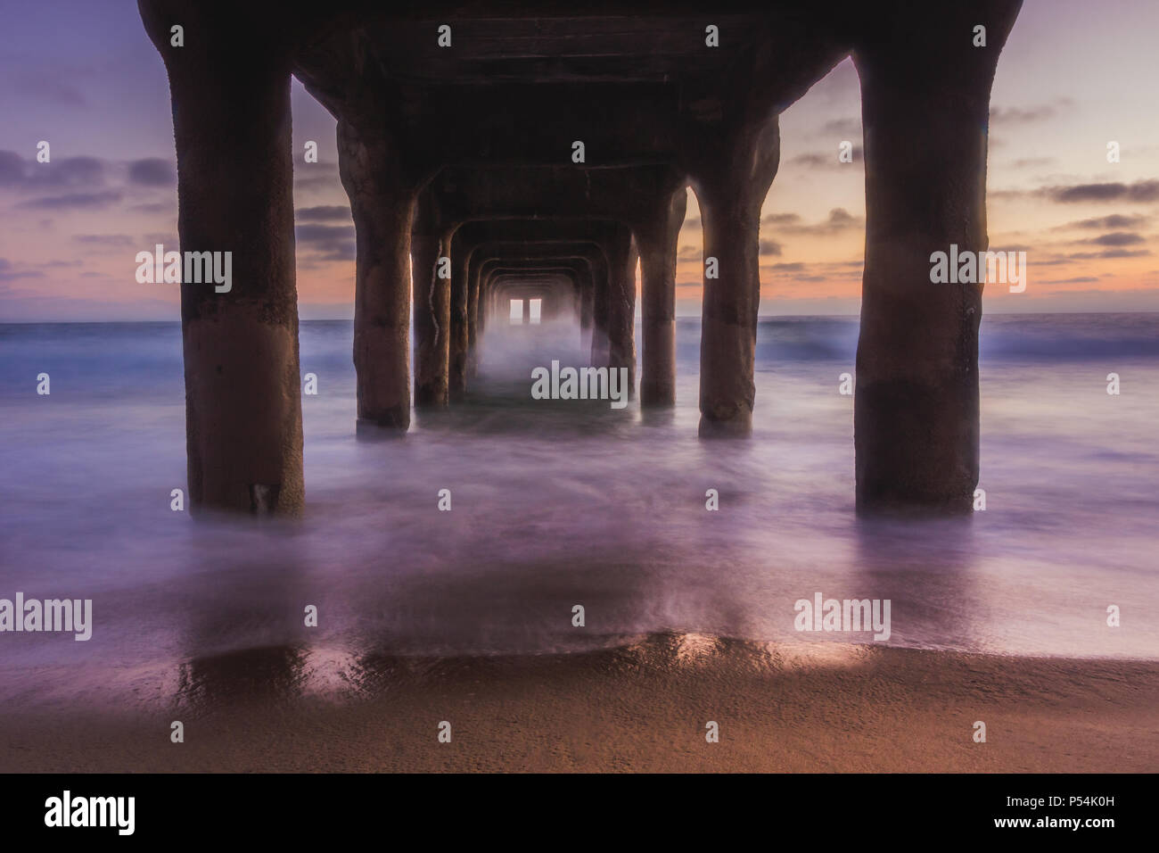 L'exposition à long terme au titre de Manhattan Beach Pier après le coucher du soleil avec des vagues de lave en douceur sur la plage, Manhattan Beach, Californie Banque D'Images