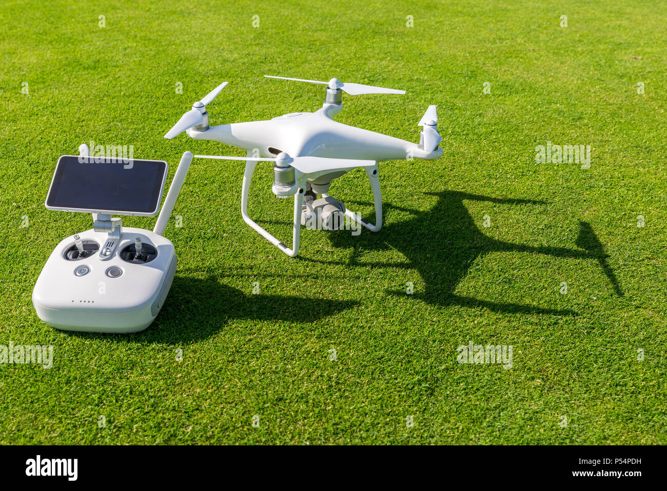 Drone quadcopter professionnel blanc avec télécommande de l'appareil photo d'en haut contre l'herbe verte en arrière-plan Banque D'Images