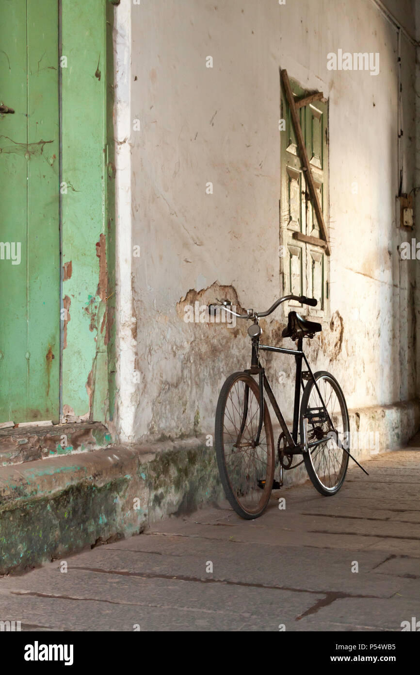 Vieux vélo calé contre le mur d'un bâtiment colonial, Kochi, Kerala, Inde SW. Banque D'Images