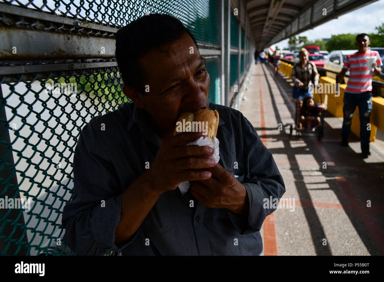 Brownsville, Texas, USA. 24 Juin, 2018. Un homme du nom de Ruben, nom d'Irène, qui a refusé de donner son nom de famille, partager un repas fourni par un groupe religieux qu'il attend sur le côté mexicain de la frontière des États-Unis il à demander asile. Plus tard, il a été admis. le long d'autres membres de la famille du Honduras. Credit : Miguel Juarez Lugo/ZUMA/Alamy Fil Live News Banque D'Images
