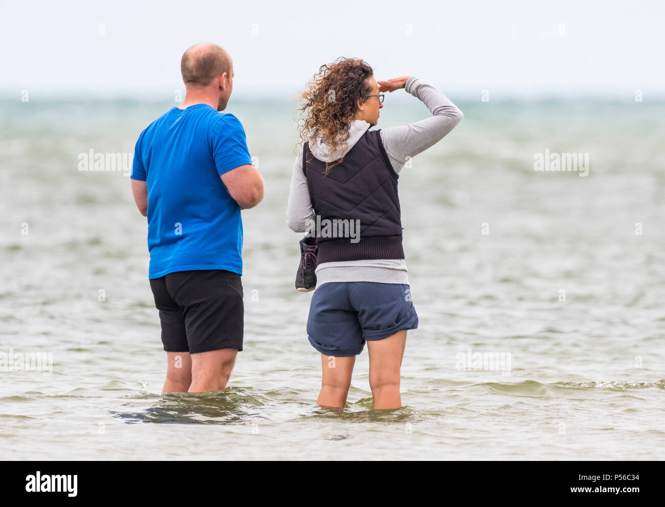 Couple de personnes portant des shorts rembourrage dans la mer. L'homme et la femme padding dans l'océan en short. Banque D'Images
