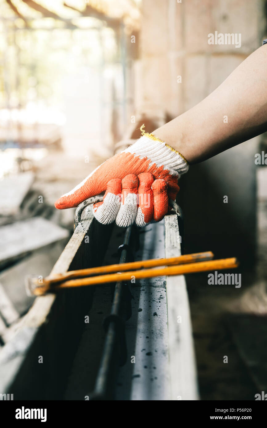 Les travailleurs de l'aide de tenailles lier les mains de fil d'acier avant d'armature béton est coulé par-dessus. Banque D'Images