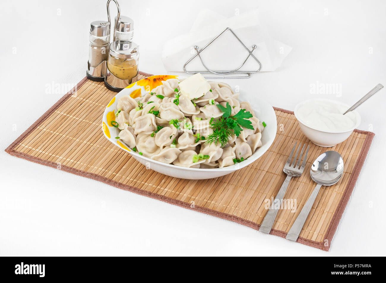 Fédération de quenelles avec les herbes et les oignons. Raviolis de viande. Le plat est servi dans une assiette. Servi avec des boulettes est la crème dans un bol. Banque D'Images