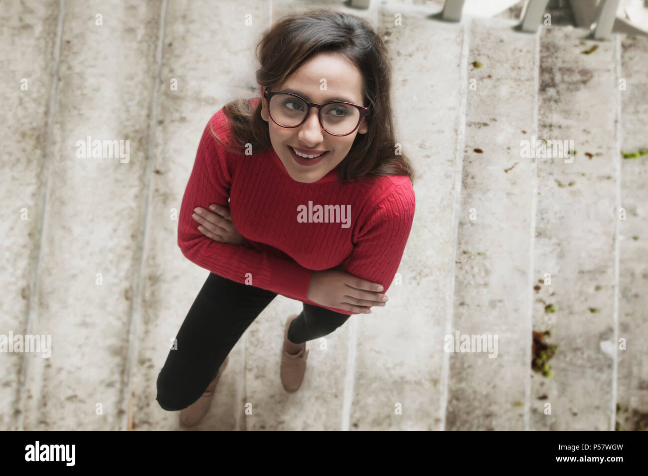 Portrait of woman standing with arms crossed on staircase looking up Banque D'Images Portrait of woman standing with arms crossed on staircase looking up Banque D'Images