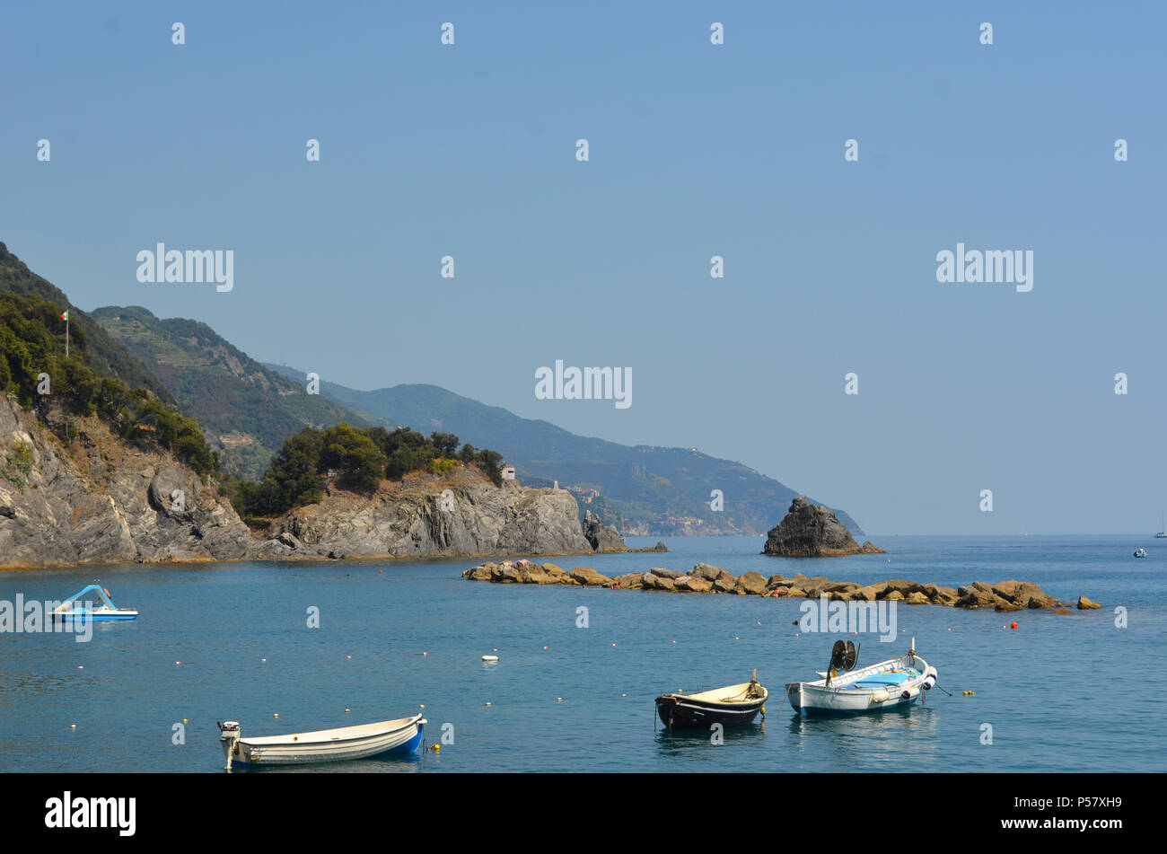 Les petits bateaux avec les moteurs hors-bord sont amarrés dans une baie tout à fait. Un brise-lames et un petit isalnd sont en face d'eux, et de collines rocheuses d'un côté le ciel. Banque D'Images