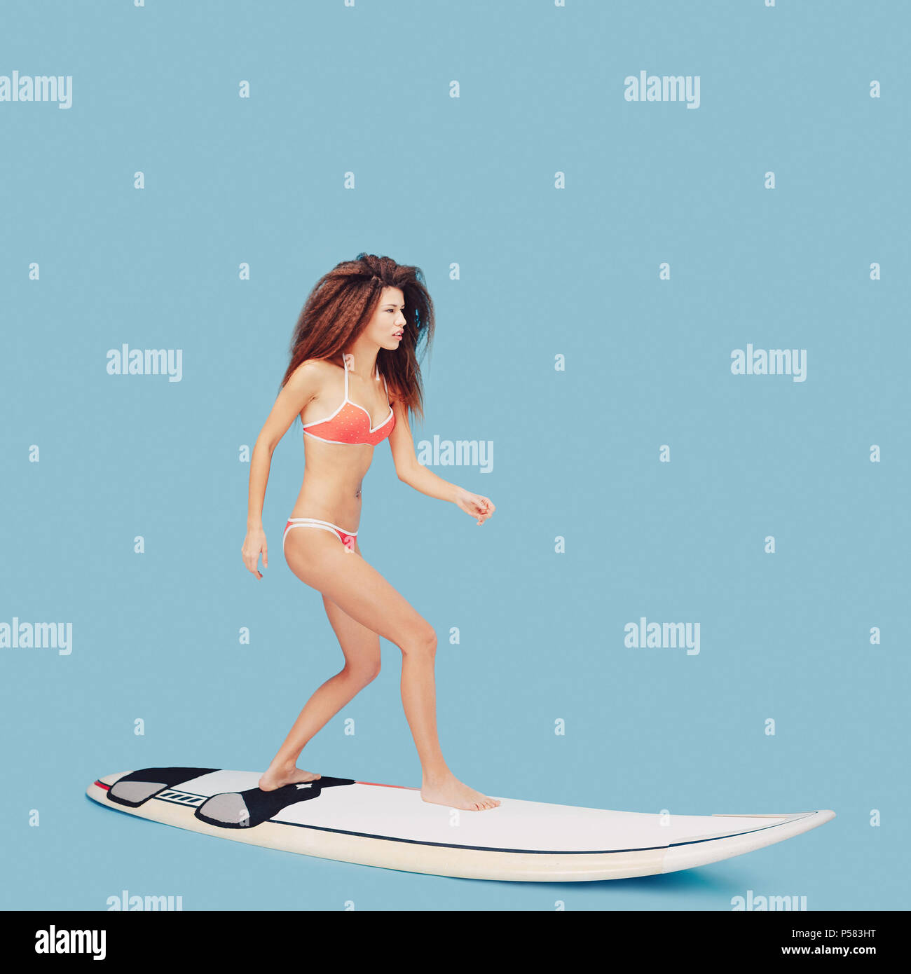Belle jeune fille debout sur une planche de surf Banque D'Images